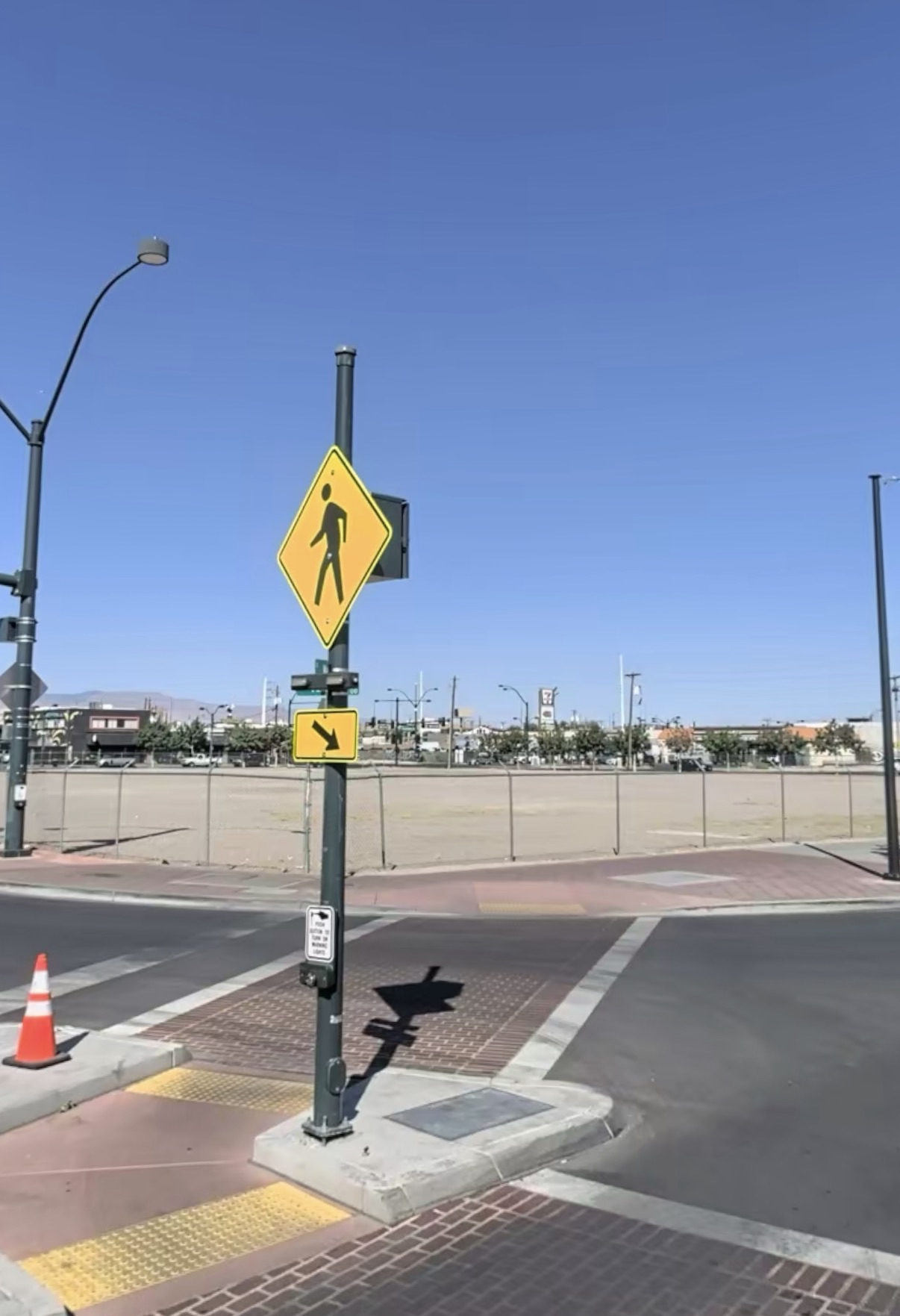 Fenced vacant downtown lot beside a crosswalk and pedestrian sign