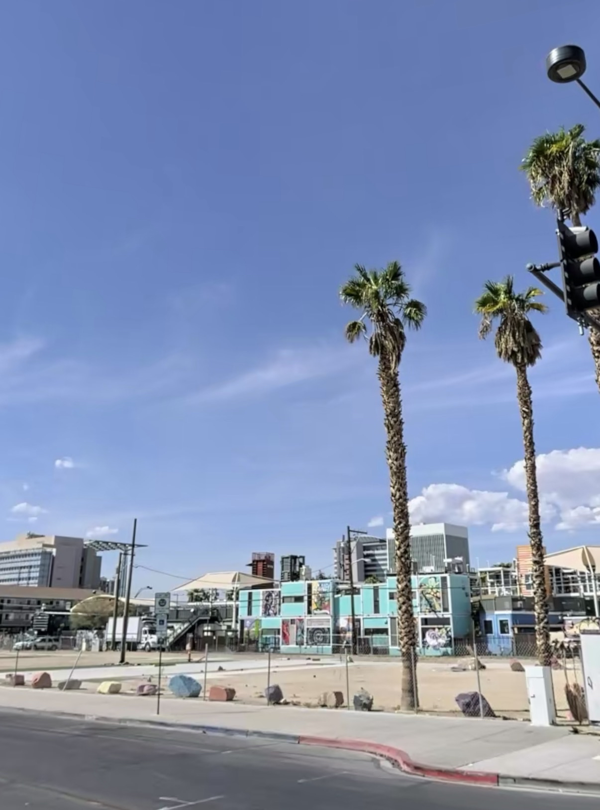 Vacant downtown lot beside palm trees and a city street