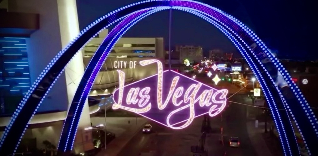 Las Vegas sign at night framed by illuminated arches